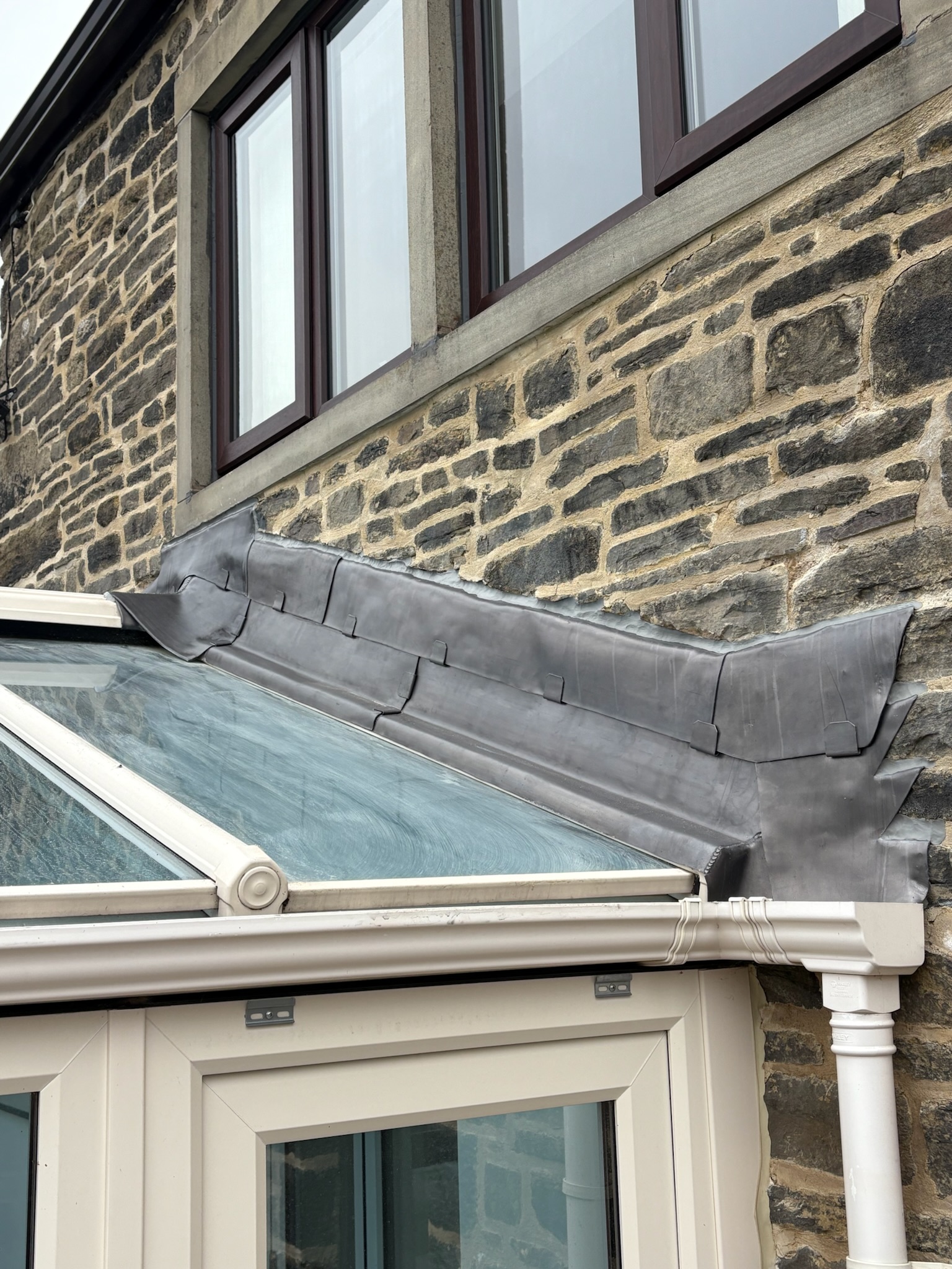 Lead flashing detail to a conservatory lapped over the interface and glazing bar